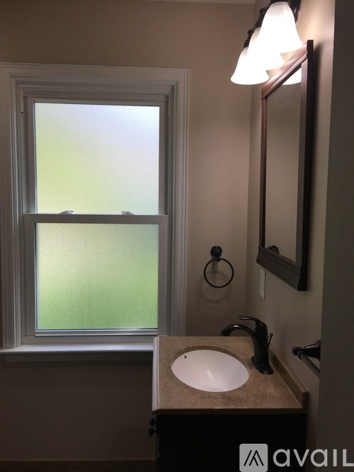 A bathroom with a sink, mirror, and a window.