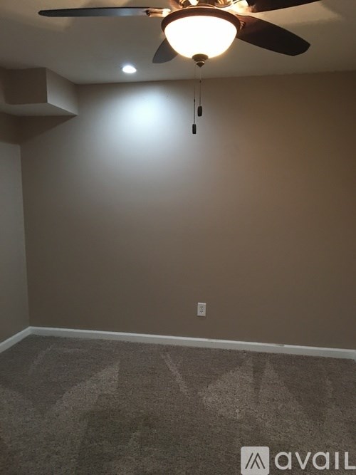 A room with a ceiling fan and carpeted floor.