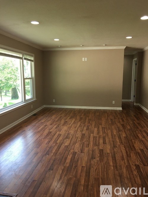 A room with wooden flooring and a window letting in natural light.
