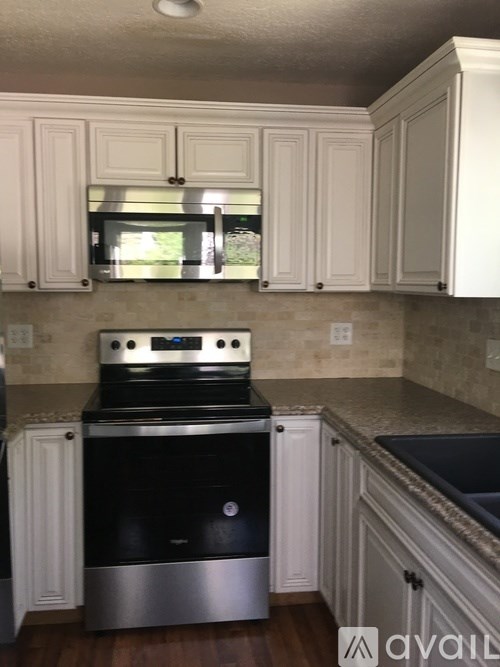 A kitchen with white cabinets and a black stove top oven.