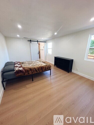 A bedroom with a bed, a television, and a window.