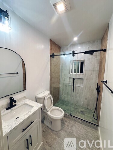 A bathroom with a toilet, sink, and shower.