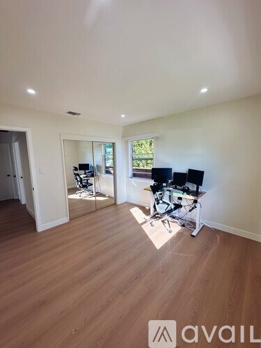 A room with wooden flooring and a large mirror on the wall.