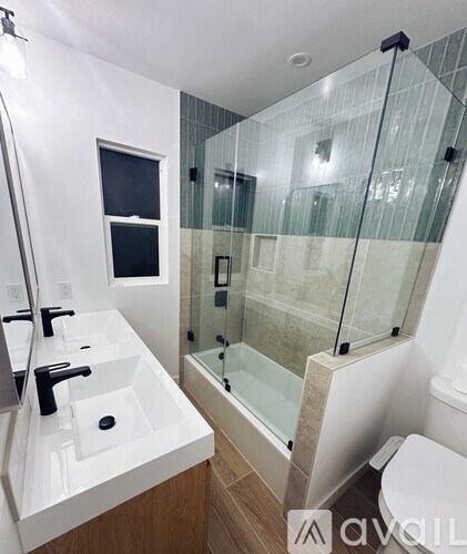 A modern bathroom with a glass shower enclosure and a white sink vanity.