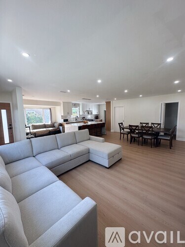 A spacious living room with a white sofa and wooden flooring.