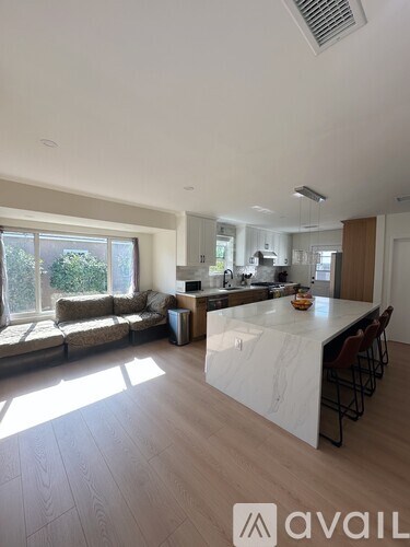 A modern kitchen with a large island and a dining area with a couch.