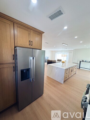 A modern kitchen with wooden cabinets and a stainless steel refrigerator.