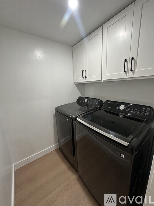 A black dishwasher and oven in a kitchen with white walls and wooden flooring.