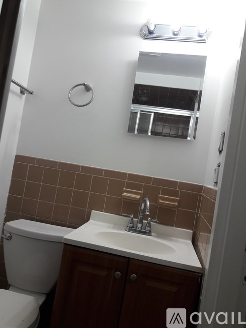 A bathroom with a toilet, sink, and mirror.