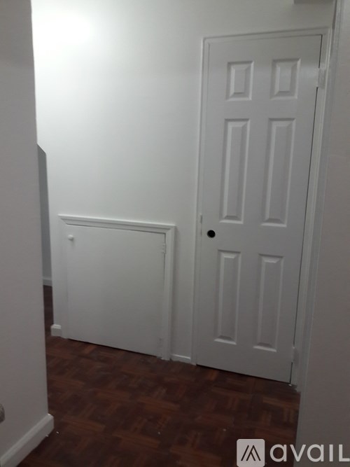 A white door with a black handle is in a room with a wooden floor.