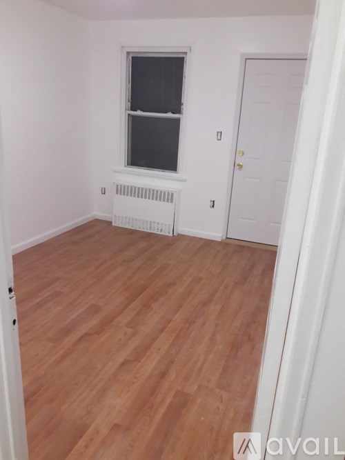 A room with wooden flooring and a white door.