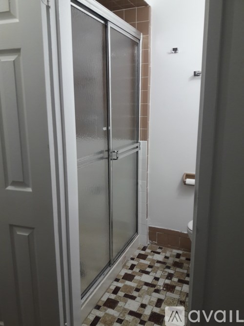 A bathroom with a glass shower door and a tiled floor.
