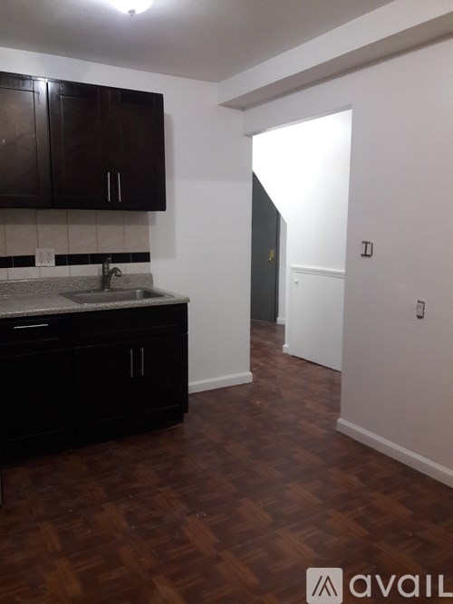 A kitchen with black cabinets and a wooden floor.