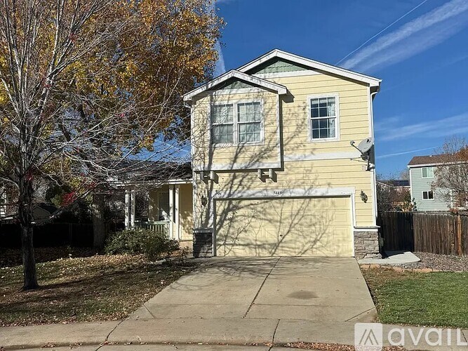 A two-story house with a garage and a tree in front.
