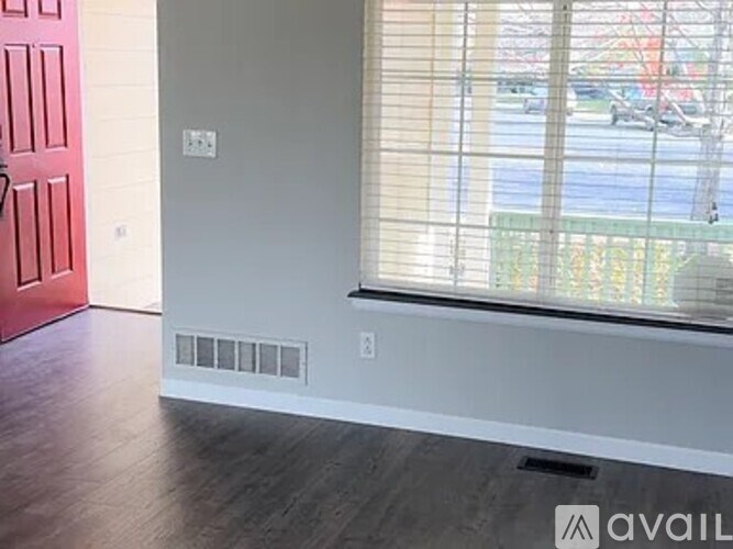 A room with a red door and a window with blinds.
