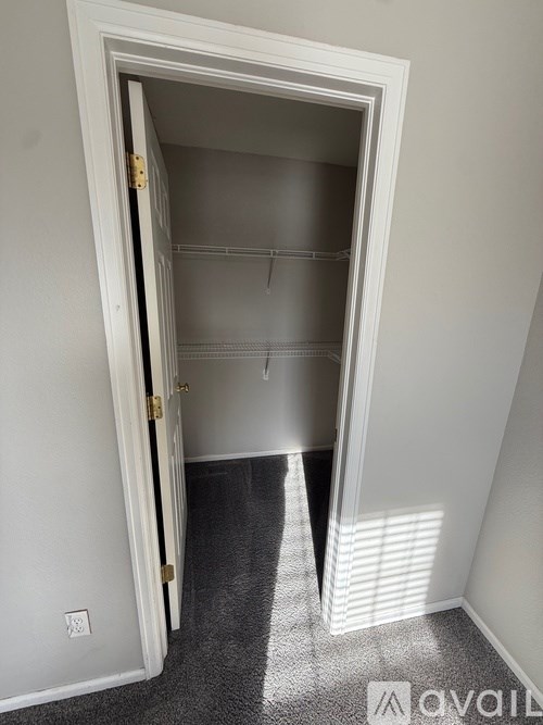 A white door with a gold handle is open to a room with a grey carpet.
