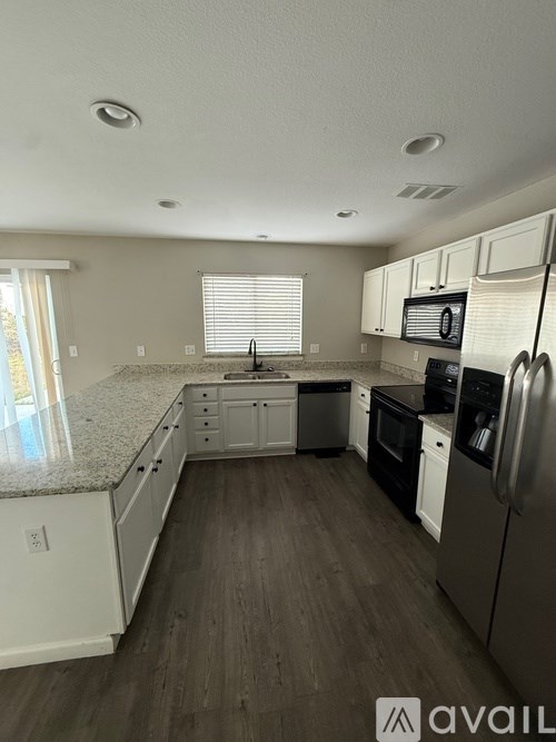 A kitchen with white cabinets and a granite countertop.