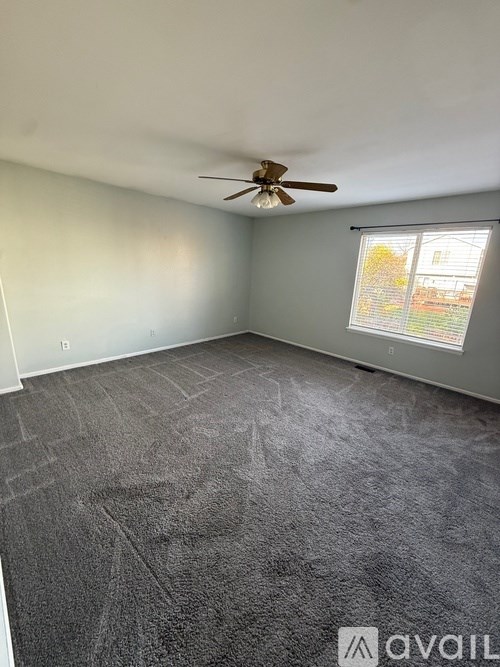 A room with a ceiling fan and a window with blinds.