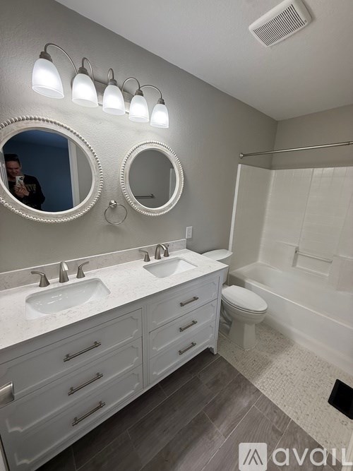 A bathroom with a vanity, mirrors, and a toilet.