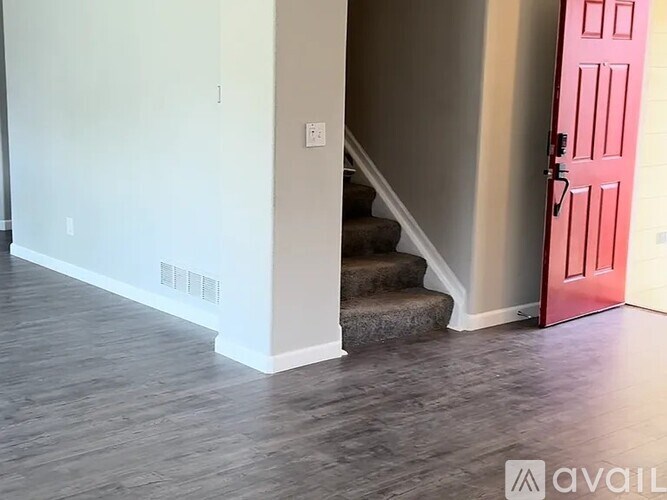 A room with a red door and a staircase.