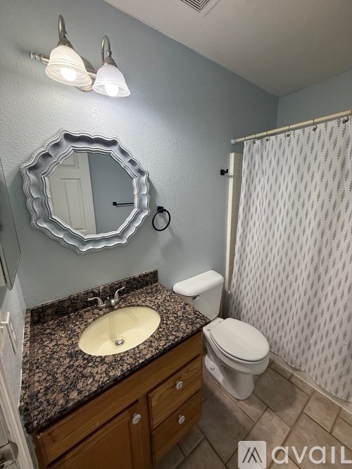 A bathroom with a sink, mirror, toilet and shower.