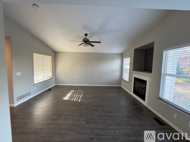 A spacious room with a ceiling fan and a fireplace.