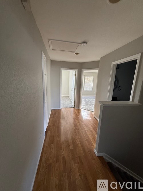 A long hallway with wood floors and white walls.