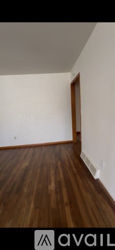 A room with wooden flooring and a white wall.