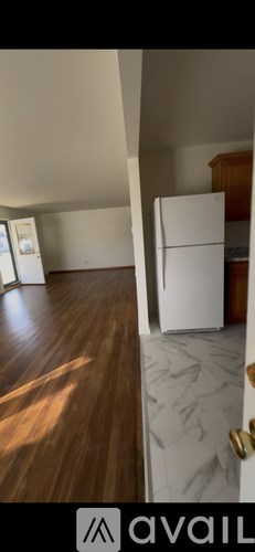 A white refrigerator is in a kitchen with wooden cabinets.