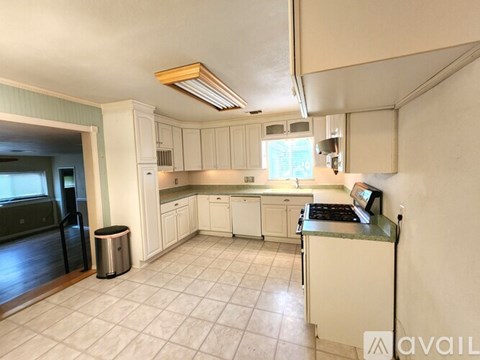 A kitchen with white cabinets and a tile floor.