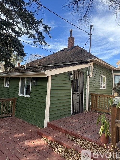 A green house with a black gate and a brick patio.