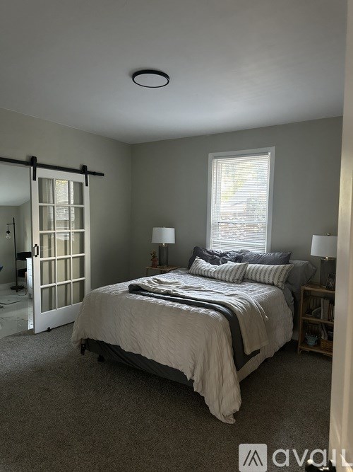 A bedroom with a bed, nightstands, and a window.