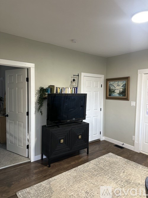 A black television set on a black cabinet in a room with white walls.