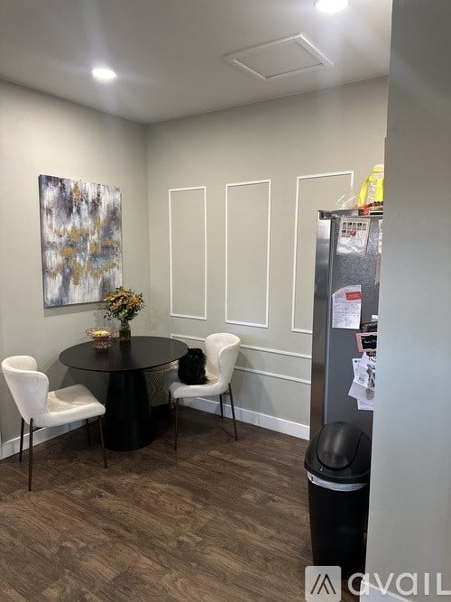 A room with a table, chairs and a fridge.