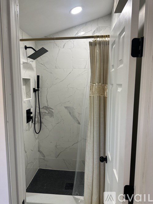 A bathroom with a marble wall and a glass shower door.