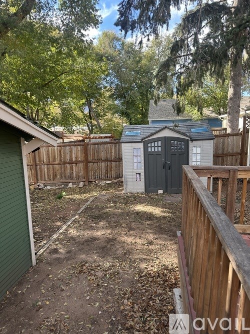 A backyard with a shed and a wooden fence.