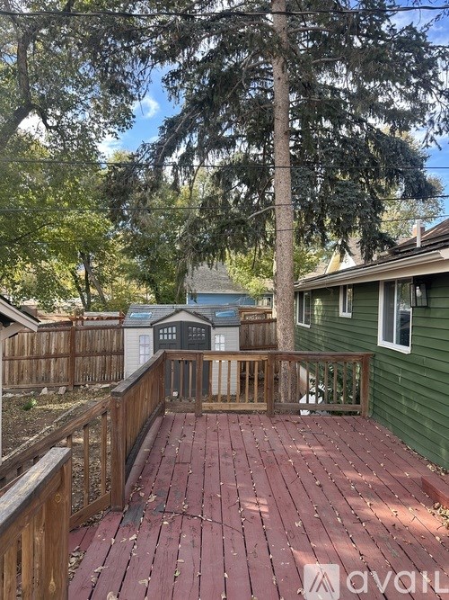 A wooden deck with a railing and a tree in the backyard.