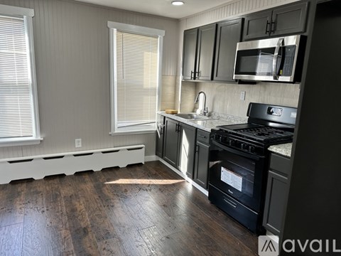 A kitchen with a black stove top oven and a black microwave above the counter.