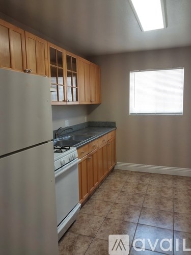 A kitchen with a refrigerator, stove, and cabinets.