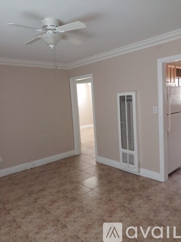 A room with a ceiling fan and a refrigerator.
