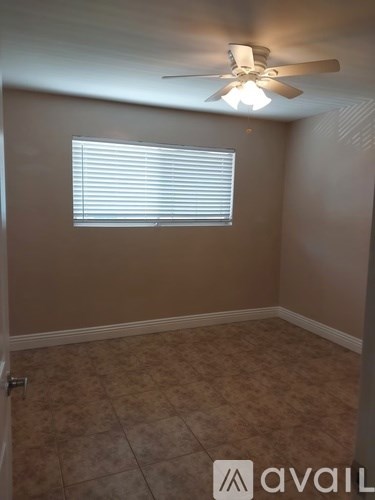 A room with a ceiling fan and a window with blinds.