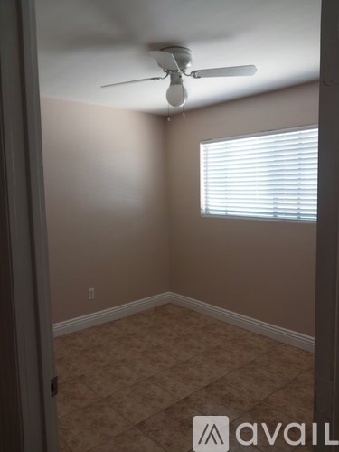 A room with a ceiling fan and a window with blinds.