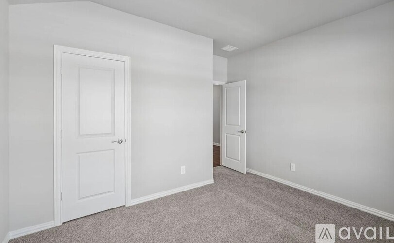 A room with a carpeted floor and two doors.