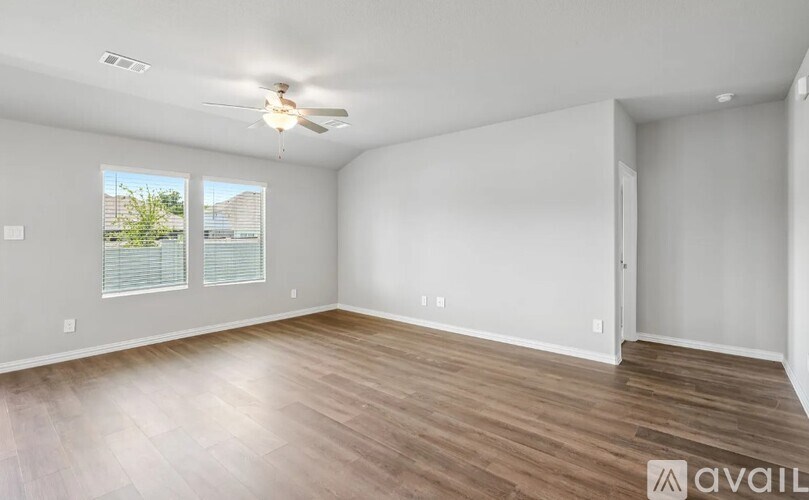 A spacious room with wooden flooring and a ceiling fan.