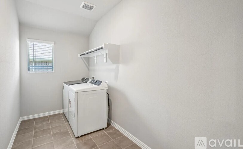 A small white refrigerator in a room with a window.