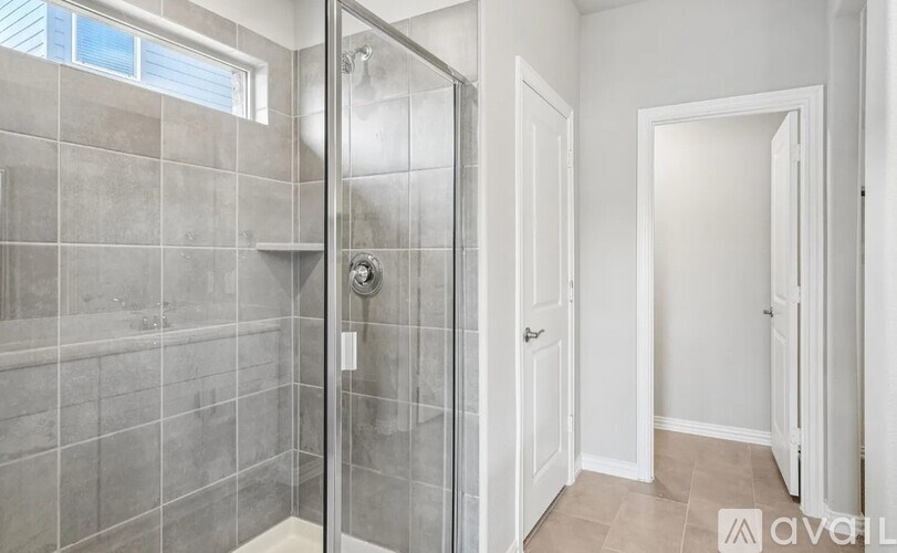 A bathroom with a walk-in shower and a white door.