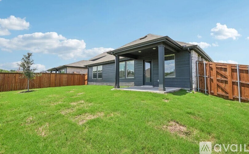 A house with a grey roof and a fence is available for sale.