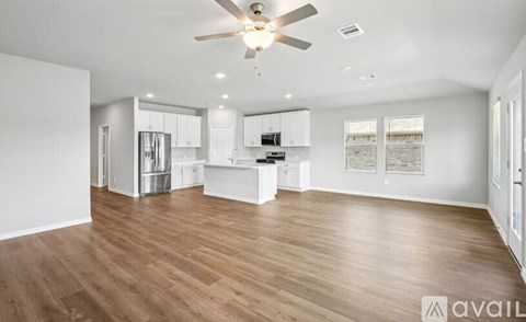 A spacious kitchen with white cabinets and a wooden floor.