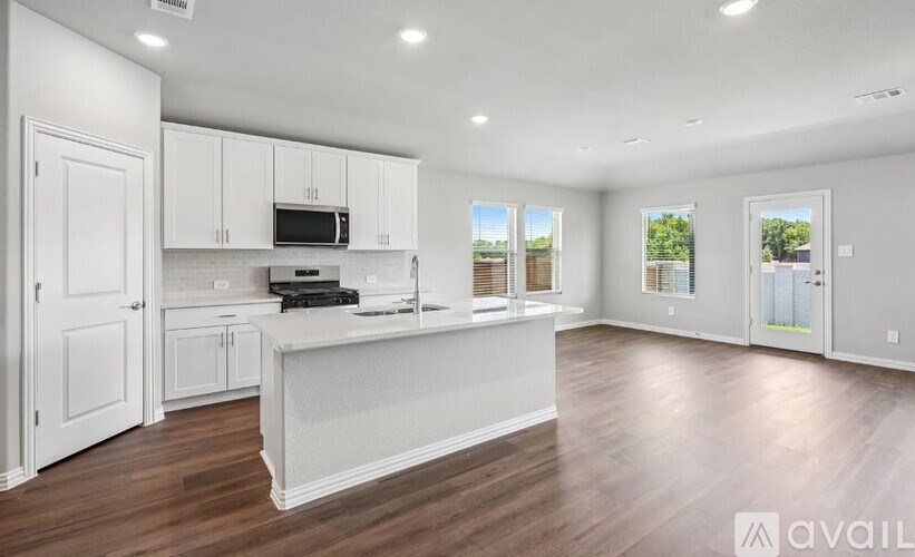 A spacious kitchen with white cabinets and a wooden floor.