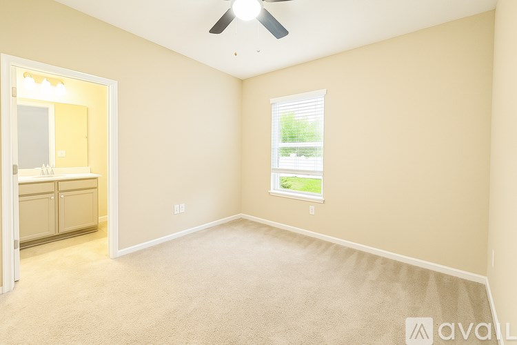 A room with a carpeted floor, a ceiling fan, and a window with blinds.